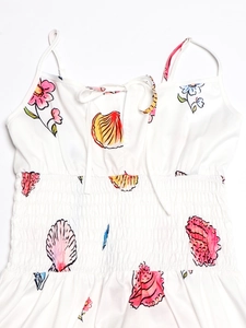 Dettaglio della vita a punto smock e motivo floreale con conchiglie su abito bianco