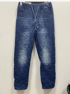 Detail of ripped blue denim pants showing elastic drawstring waist and whiskered texture