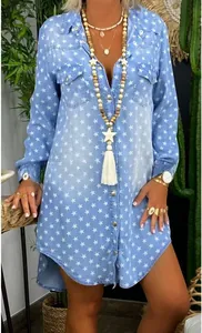 Detail of light blue denim shirt dress featuring white star prints and chest pockets
