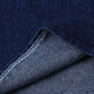 Macro shot of dark blue denim fabric showing detailed white overlock stitching and texture