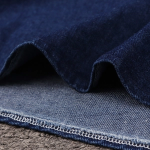 Detail of dark blue denim fabric showing twill weave and precise white contrast stitching