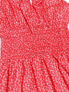 Dettaglio dell abito rosso a fiori con vita elastica a punto smock e stampa fiocchi