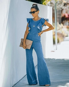 Blue denim jumpsuit with ruffle sleeve detail and flared leg design in outdoor lighting