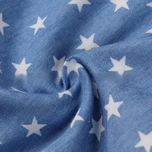 Detail of blue denim fabric featuring white star print and diagonal twill weave texture