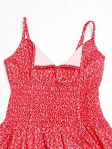 Dettaglio dell'abito floreale rosso con corpetto a punto smock e motivi a cuore