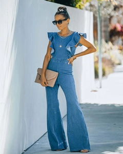 Detail of blue denim jumpsuit featuring ruffle sleeves and waist hollow-out design