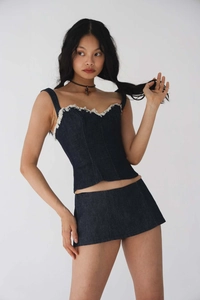 Détail du haut corset en denim bleu foncé à bords bruts avec une mini-jupe assortie