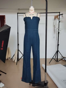 Detail of blue denim jumpsuit featuring a V-notch tube top design and wide leg cut