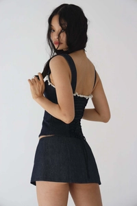 Détail de l'ensemble en jean bleu foncé avec bords frangés blancs et laçage au dos