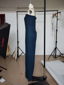 Detail view of a slim fit dark wash denim jumpsuit showing the side profile on a mannequin