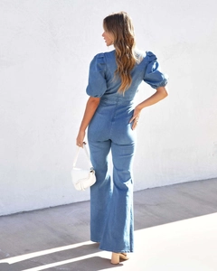 Detail of light blue denim jumpsuit with puff sleeves and wide leg back view on model