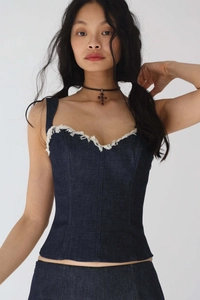 Détail d'un haut bustier en jean bleu avec décolleté en V profond et bordures effilochées