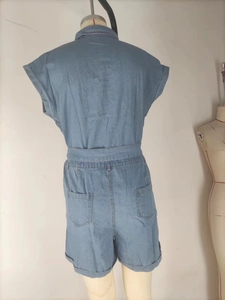 Rear view of light blue denim romper featuring buttoned collar and waist belt detail