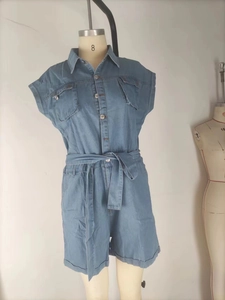 Detail of light blue denim short jumpsuit with lapel collar and chest flap pockets