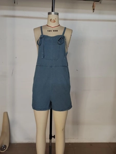 Detail view of blue washed denim overalls featuring chest pocket and rolled hem design