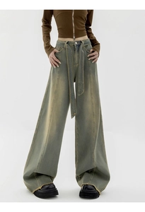 Detail of high waisted wide leg jeans featuring retro wash finish and frayed raw hem