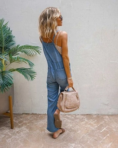 Detail of light blue denim overalls with crisscross back straps and rolled-up cuffs