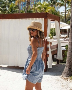 Detail of light blue denim romper featuring smocked bodice and delicate spaghetti straps