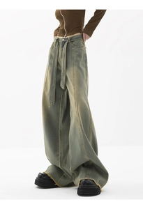 Detailed view of high-waisted wide leg jeans with vintage wash and distressed raw hem edge