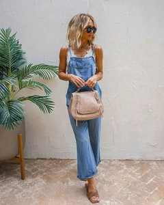Detail view of light blue denim overalls with front pocket and cotton texture