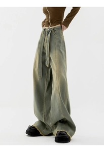 Detailed macro view of vintage dirty-wash wide-leg denim pants with raw hem and belt