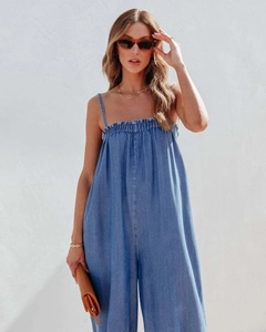 Close-up of light blue denim jumpsuit featuring thin straps and elastic pleated neckline
