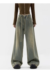 Detail of vintage washed wide-leg jeans with long denim belt and frayed hem accents