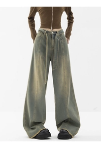 Detail of wide-leg vintage wash jeans with vertical pleats and matching fabric belt