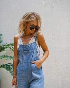 Detail of light blue washed denim dungarees with large pocket and lace strap top