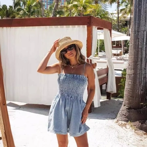 Summer light blue smocked denim romper with spaghetti straps in a beach vacation setting