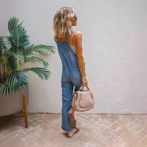 Women's light blue washed denim overalls with crisscross back straps and boho accessories