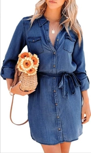 Close-up of women's blue denim shirt dress showing button closure and waist tie detail