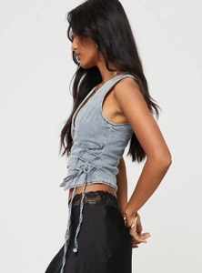 Detail of light blue denim crop top with side lace-up drawstring and button closure