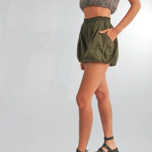 Dettaglio di pantaloncini a palloncino verde oliva a vita alta con elastico e tasche
