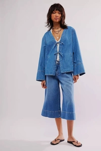 Détail d'un ensemble en jean bleu clair avec veste à nouer et pantalon large court chic