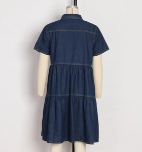 Rear view detail of dark blue denim dress showing layered tiered skirt and yellow stitching