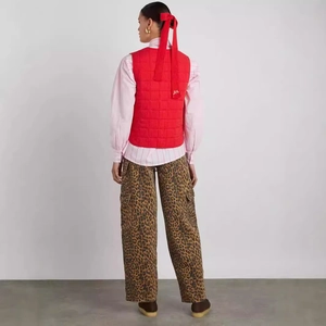 Detail of red quilted vest featuring a back bow tie and delicate DM letter embroidery