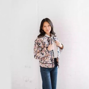 Detail of floral quilted cotton jacket with pink flower pattern and black piping accents