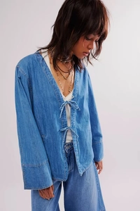 Détail de la veste kimono en jean bleu clair délavé avec nœuds et coupe bohème décontractée