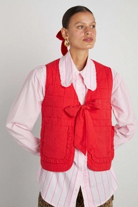 Detail of red quilted vest with bow-tie closure and delicate ruffle trim on pockets