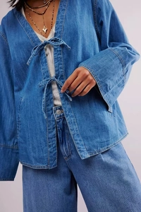 Gros plan détaillé d'une veste en jean bleue avec laçage à l'avant et manches évasées