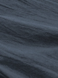 Close-up detail of blue-grey cotton linen fabric showing woven texture and natural wrinkles