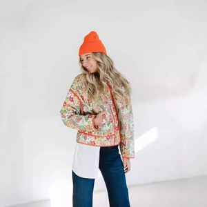 Detailed view of floral quilted jacket with orange piping and matching knit beanie cap