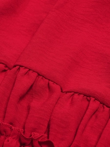 Detail of red backless dress showing textured woven fabric and fine pleated ruffles