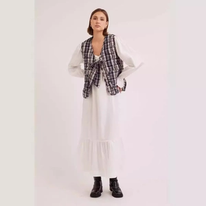 Street style outfit with white ruffle hem dress and black and white checkered quilted vest