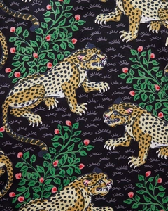 Macro detail of high-quality fabric showing a leopard print with green leaves and red berries