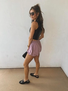 Dettaglio degli shorts viola con vita elastica e crop top nero con accessori moda