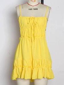 Detail of yellow backless dress featuring thin straps and tiered ruffle layers