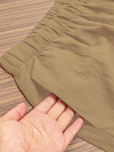 Close-up of elastic waistband and functional side pockets on khaki casual trousers