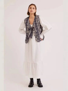Women's white ruffle dress with black and white plaid quilted vest and lace-up front detail